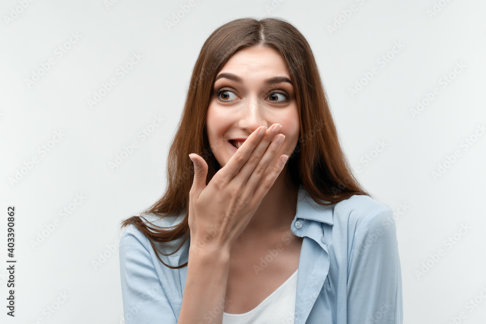 Charismatic Caucasian girl is giggling and covers her mouth with her hand. Human emotions, facial expression concept. Charismatic Caucasian girl is giggling and covers her mouth with her hand. Human emotions, facial expression concept.