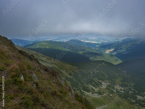 View of valley from grassy hill slopes of hiking trail from Chopok at mountain meadow landscape of ridge Low Tatras mountains Nature park, Slovakia. cloudy late summer day © Kristyna