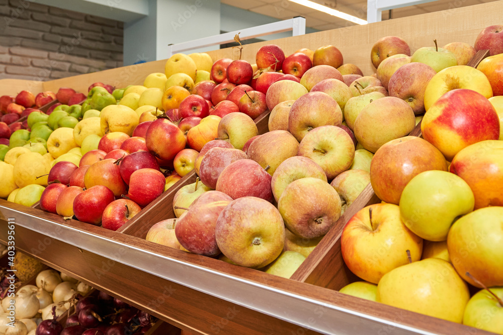 Multicolored apples in wooden boxes on store shelves