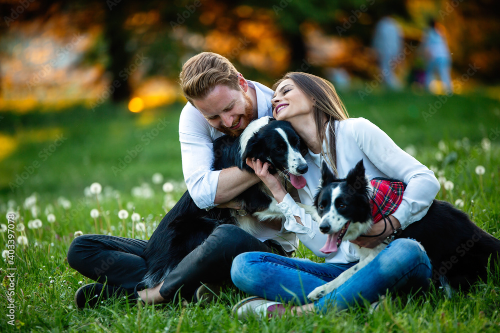 Fototapeta premium Happy couple in love playing with dogs in the park
