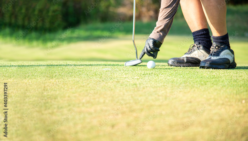 Obraz premium Close up Hand asian woman putting golf ball on tee with club in golf course on sunny day for healthy sport. Lifestyle Concept.