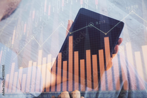 Double exposure of man s hands holding and using a digital device and forex graph drawing. Financial market concept.