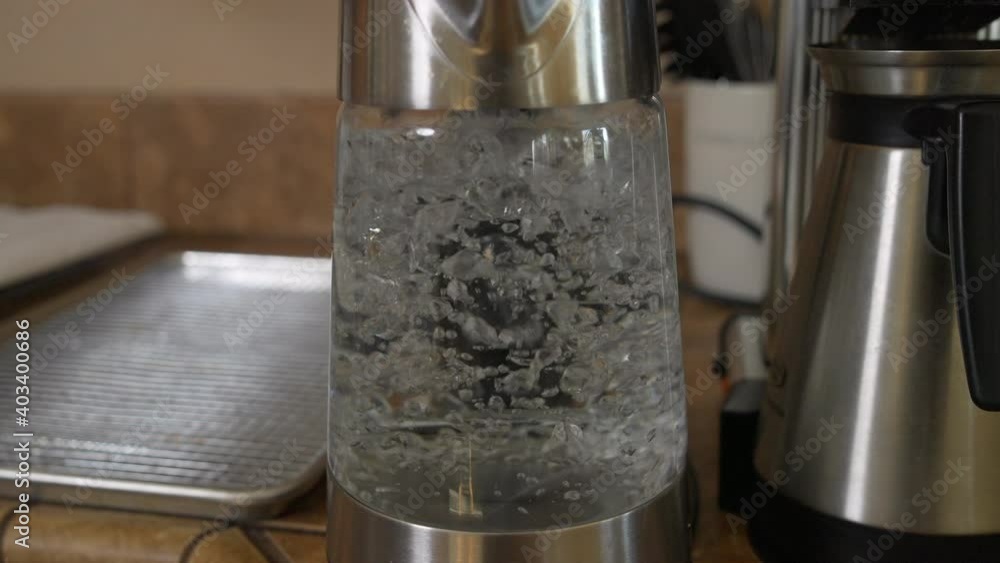 Water boiling and bubbling in clear glass kettle by coffeemaker Water boiling and bubbling in clear glass kettle by coffeemaker