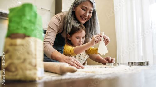 Little granddaughter holding raw cookie near grandmother