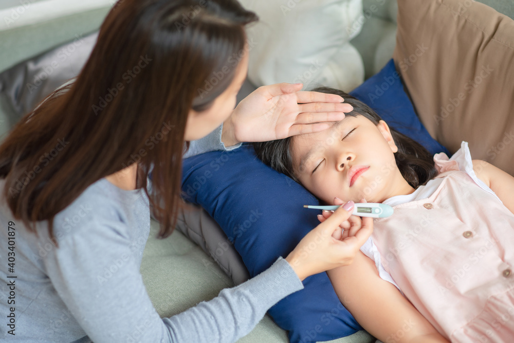 Asian mother checking her kid body temperature by thermometer which got fever and illness at home. Asian mother checking her kid body temperature by thermometer which got fever and illness at home.