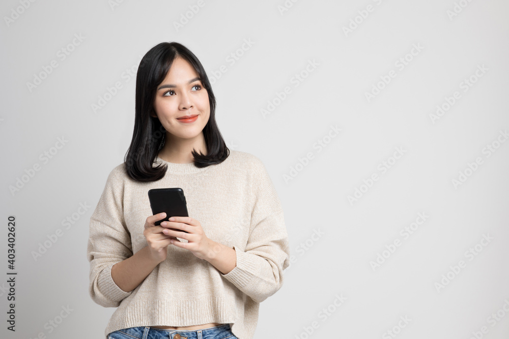 Beautiful young asian woman holding smartphone standing on isola Beautiful young asian woman holding smartphone standing on isola