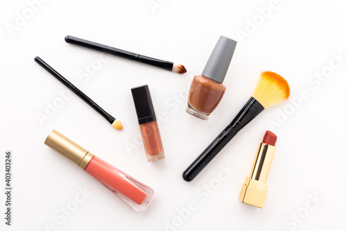 Plenty of makeup on the white table with eyelash brush, eye shadow, lipstick.