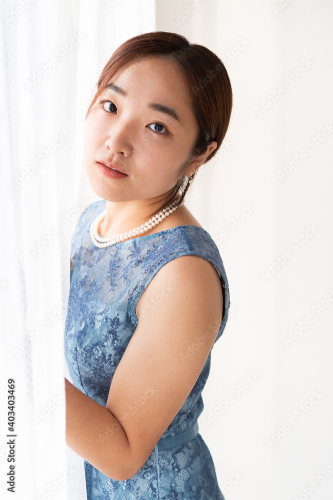 窓の前に立つドレスを着た女性
窓の前に立つドレスを着た女性
