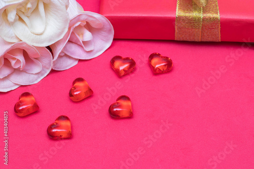 Congratulations on Valentine's Day: roses, a gift box and hearts on a red background, copy space. The photo