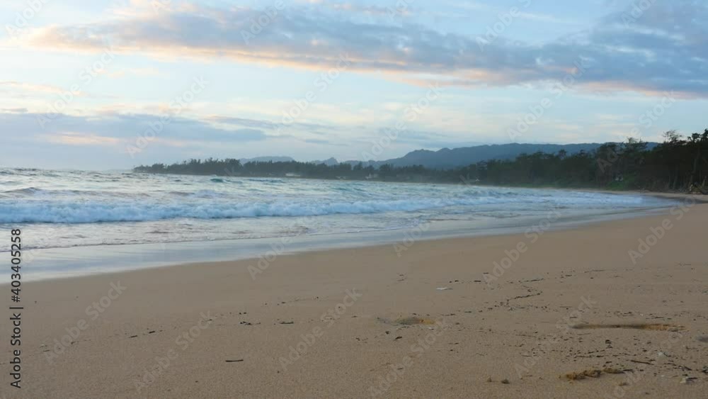 A remote beach on North Shore oahu with rough surf at sunset. Pacific ocean. Golden sand. Pink clouds. Purple sky A remote beach on North Shore oahu with rough surf at sunset. Pacific ocean. Golden sand. Pink clouds. Purple sky