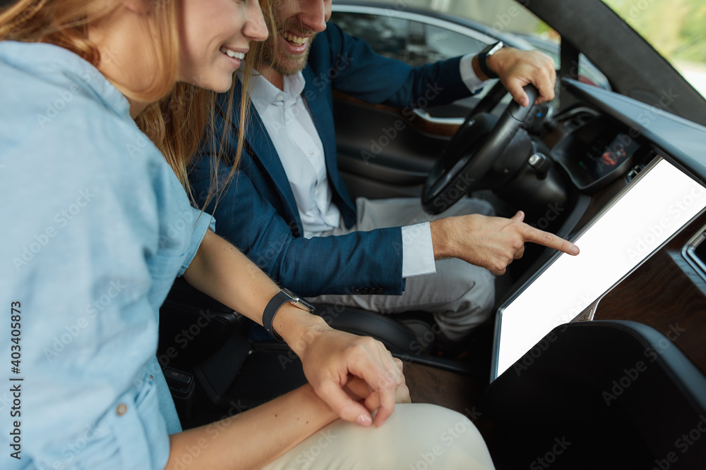 Happy young couple looking into screen of car computer Happy young couple looking into screen of car computer