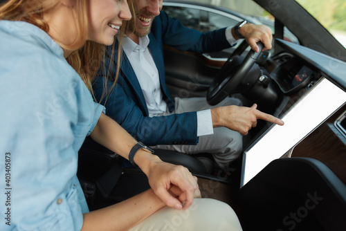Happy young couple looking into screen of car computer