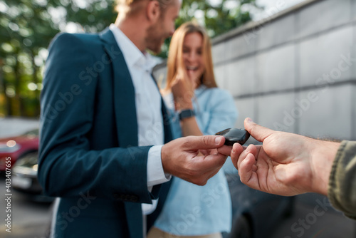 Sales manager giving car keys to young caucasian man