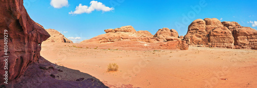 Rocky massifs on red sand desert, bright blue sky in background - typical scenery in Wadi Rum, Jordan