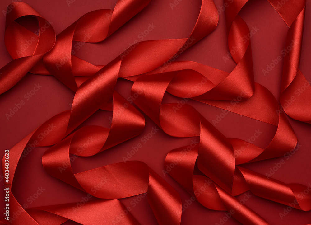 curled red silk ribbon on a red background curled red silk ribbon on a red background