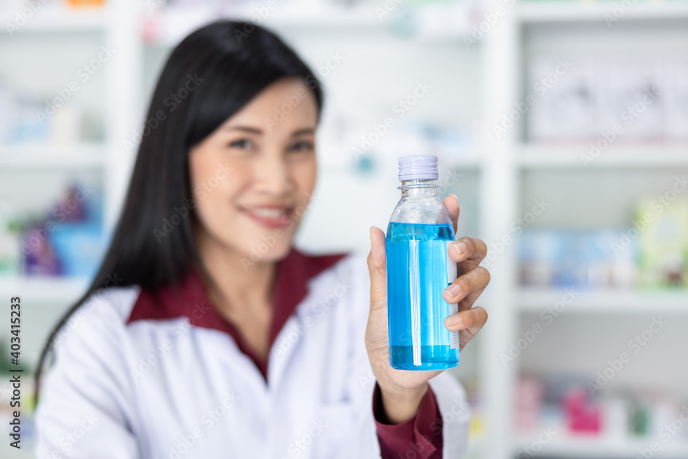 asian female pharmacist show bottle hand gel in drugstore asian female pharmacist show bottle hand gel in drugstore