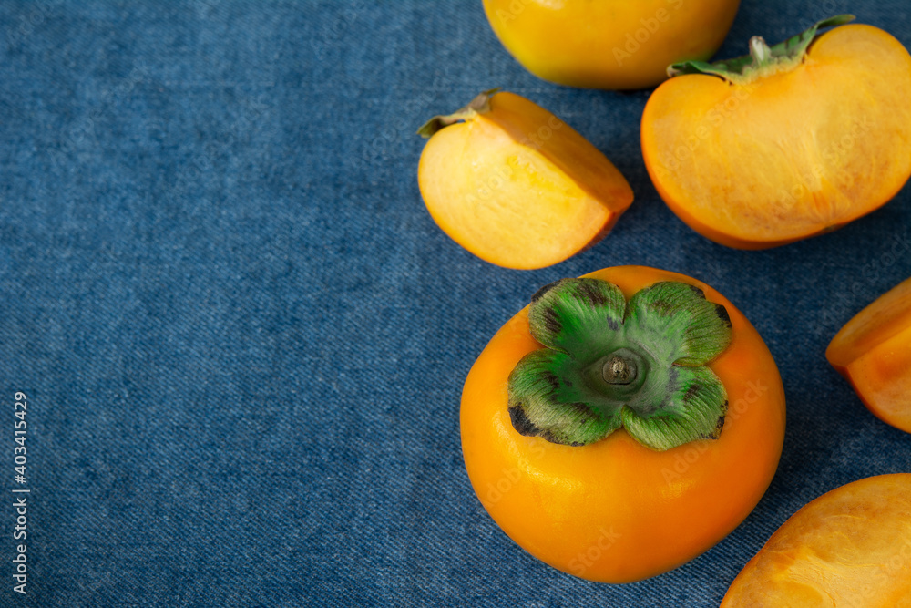Persimmon on blue cloth support floor background.Disease prevention,healthy fruit high in vitamin C Persimmon on blue cloth support floor background.Disease prevention,healthy fruit high in vitamin C