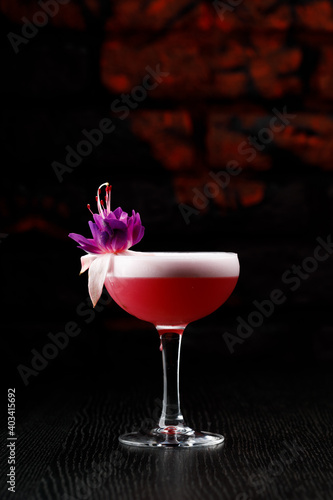 Pink alcoholic cocktail in a glass on a black table.