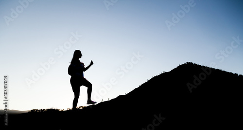 Silhouette of a woman giant strides along the mountainside as on a career ladder. Travel or business success.