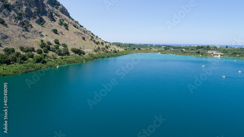 Beautiful scenery of the island from a bird's-eye view. Kataramarans sail along a blue lake against the background of green mountains and the city.