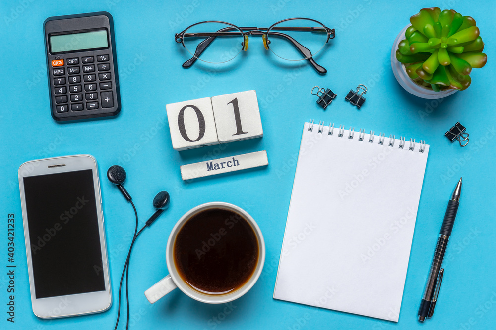 Office workplace with coffee cup, smart phone, calculator, stationery and plant. Date 01 March on wooden block calendar. White blank empty notepad page. Table desk top view, flat lay, copy space Office workplace with coffee cup, smart phone, calculator, stationery and plant. Date 01 March on wooden block calendar. White blank empty notepad page. Table desk top view, flat lay, copy space