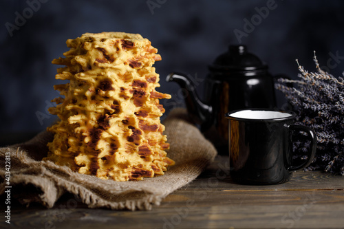 Shakotis is a national Lithuanian baking. Black kettle and cup on the table on a black background.
