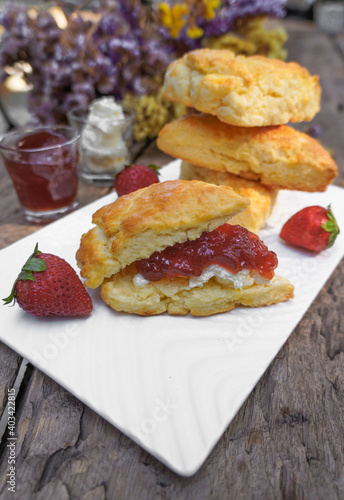 Scones and Strawberry Jam, Clotted cream in a white plate on a wooden table
