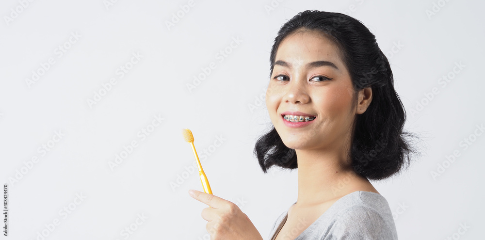 Dental brace teenager girl smile holding toothbrush and looking to camera. white teeth with blue braces. Dental care. Asian woman with contact lens and orthodontic accessories. Cosmetic dentistry. Dental brace teenager girl smile holding toothbrush and looking to camera. white teeth with blue braces. Dental care. Asian woman with contact lens and orthodontic accessories. Cosmetic dentistry.