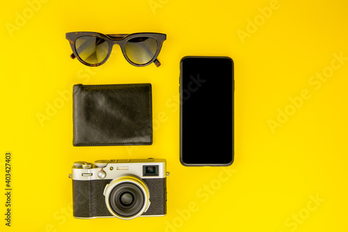 vintage camera, wallet, glasses, phone on the yellow backround with copy space.