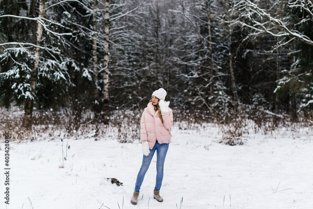 a beautiful girl in white fluffy mittens, a hat and light clothes with a surprised face and open mouth stands in a snowy park a beautiful girl in white fluffy mittens, a hat and light clothes with a surprised face and open mouth stands in a snowy park