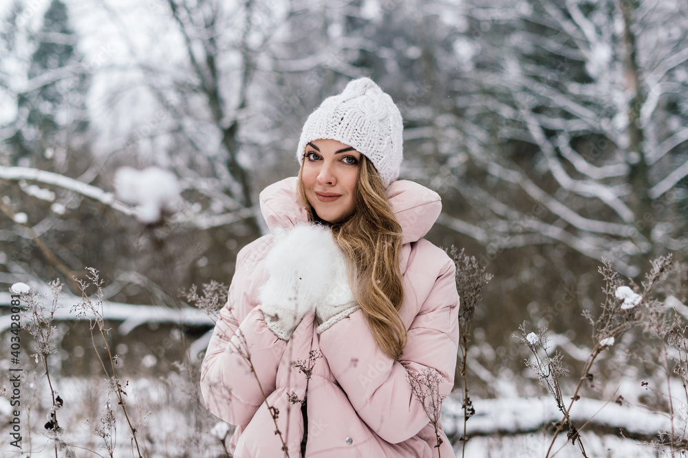 young beautiful woman in a snowy park, among the bare snow-covered branches and tall dry grass covered with snow young beautiful woman in a snowy park, among the bare snow-covered branches and tall dry grass covered with snow