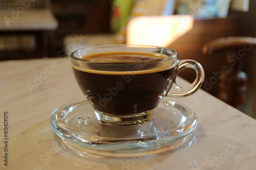 Hot black coffee in a transparent cup isolated on the table 