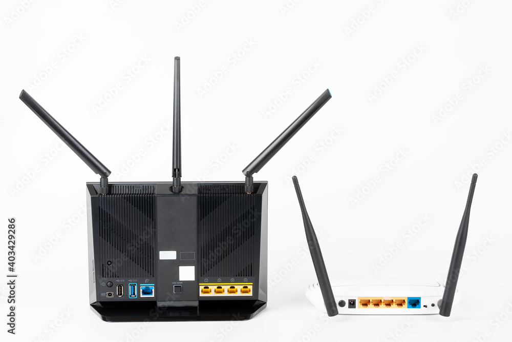 Fototapeta premium Rear view of two Wi-Fi routers, wireless devices with two and three antennas. Black router has five Gigabit Ethernet ports, ultrafast USB 3.1 port and USB 2.0 port. 