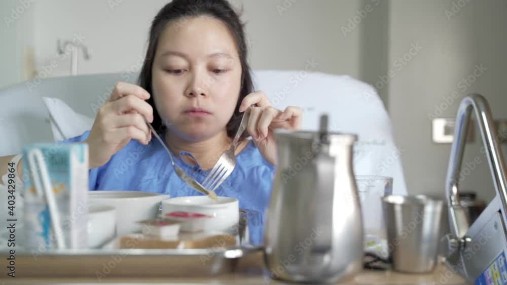 asian female patient enjoy eating hospital food in bed. copy space provided. asian female patient enjoy eating hospital food in bed. copy space provided.