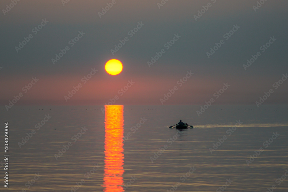 a boat going into the sunset over a sea clear sky