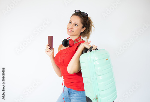 Happy European girl with suitcase and pass isolated on white background excited about trip