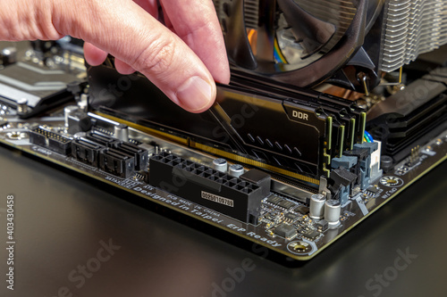 Computer technician installs new RAM DDR memory into a PC. Computer upgrade or repair concept. Close-up