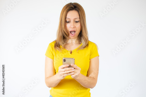 young woman using mobile over isolated background with a confident expression on smart face surprised