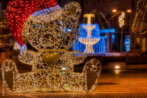 Huge illuminated teddy bear figure in santa hat on the main square of Szombathely, Hungary during the advent