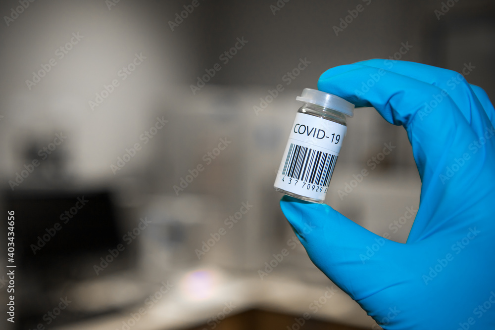Coronavirus vaccination dose ready for immunisation. Doctor with gloved hands holding a glass vial of covid-19 vaccine