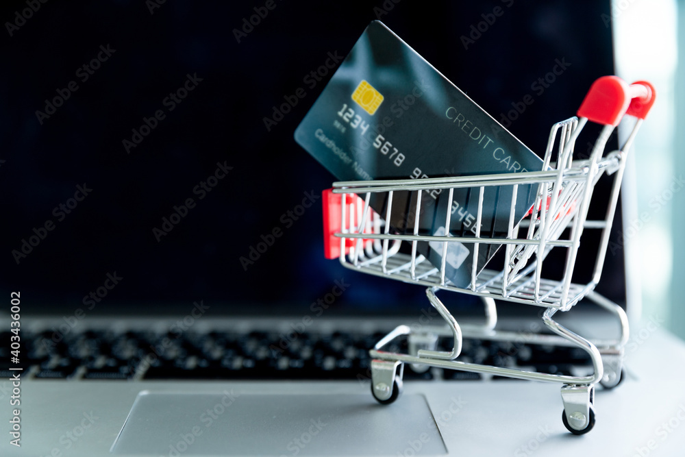 Concept online shopping. Toy supermarket cart on laptop computer.