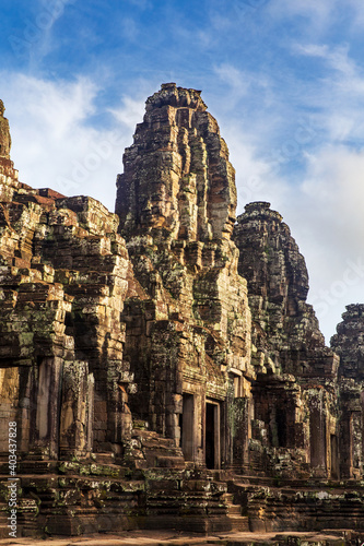Sunrise on a face tower in the Bayon temple in Angkor Thom, Angkor. Cambodia. Vertical view.