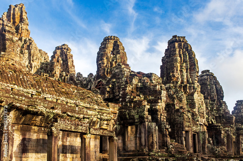 Sunrise on some of the face towers in the Bayon temple in Angkor Thom, Angkor. Cambodia. Vertical view.