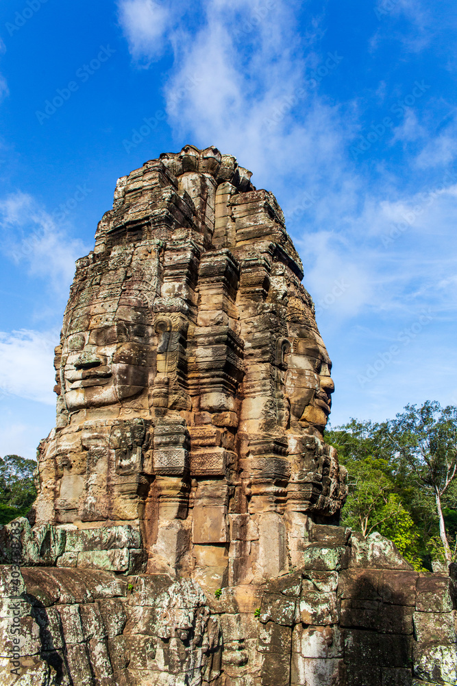 Face tower in the Bayon temple in Angkor over blue sky. Cambodia. Vertical view.