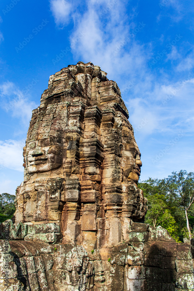 Fototapeta premium Face tower in the Bayon temple in Angkor over blue sky. Cambodia. Vertical view.