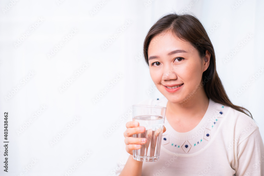 Cheerful Asian young woman drinking a water in a glass close up with copyspace. Cheerful Asian young woman drinking a water in a glass close up with copyspace.