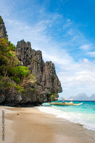 Banca boat on the white sand pristine beach of Entalula island in El nido, region of Palawan in the Philippines. Vertical view.