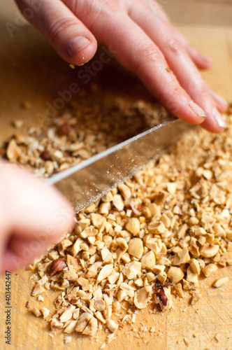 Closeup of a chef chopping nuts with a knife on wooden table