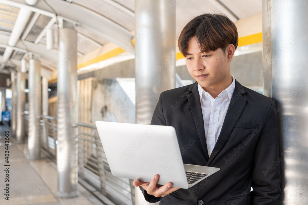 Portrait of handsome business man standing with a laptop outside the office. Portrait of handsome business man standing with a laptop outside the office.