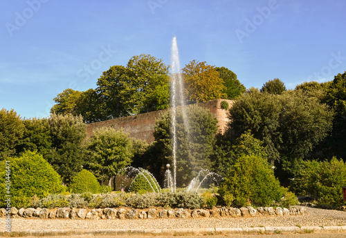 View of the Fountain of St Prospero with the Medici Fortress (Italian: Fortezza Medicea, 16th century) in the background in a sunny summer day, Siena, Tuscany, Italy